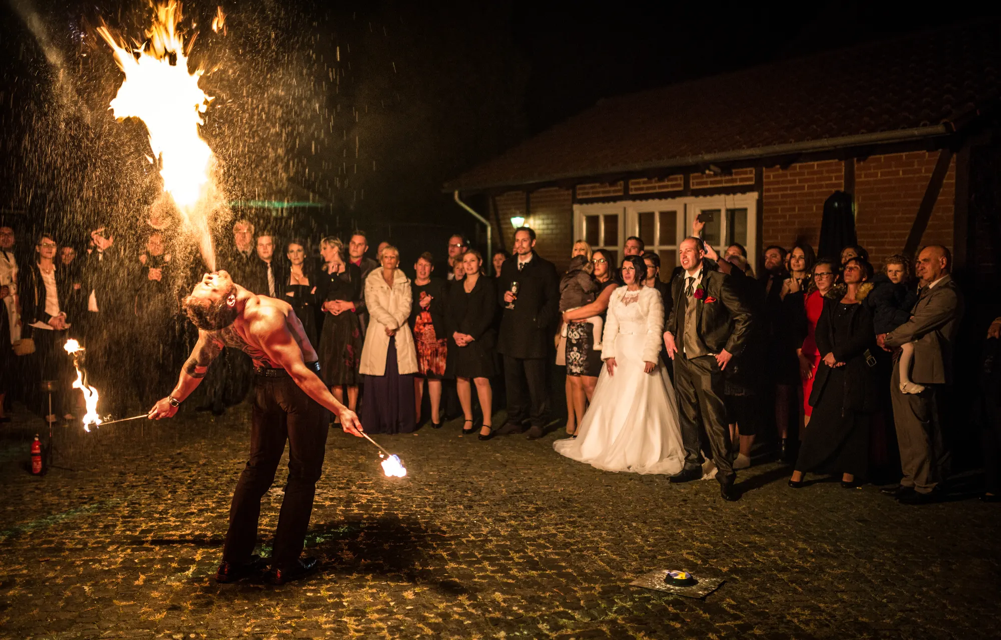 Feuerkünstler spuckt Feuer, Brautpaar und Gäste schauen zu